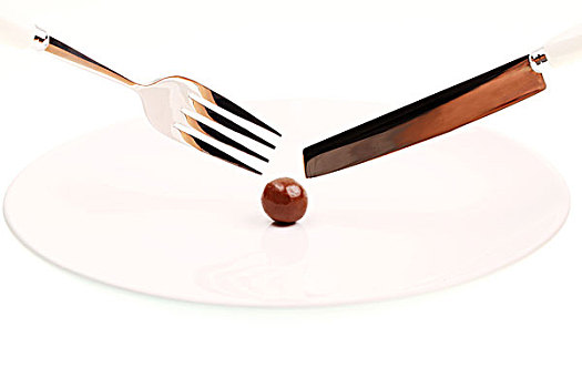白色盘子中的一个圆形棕色巧克力豆和银色刀叉