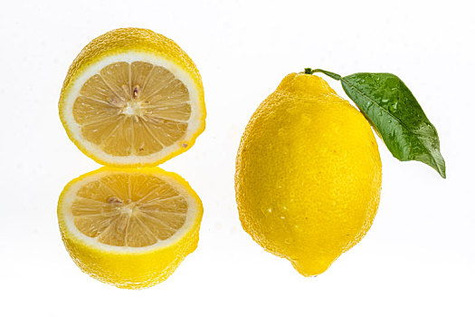 一个切成两半的柠檬和一个完整的柠檬放置在白色的背景中