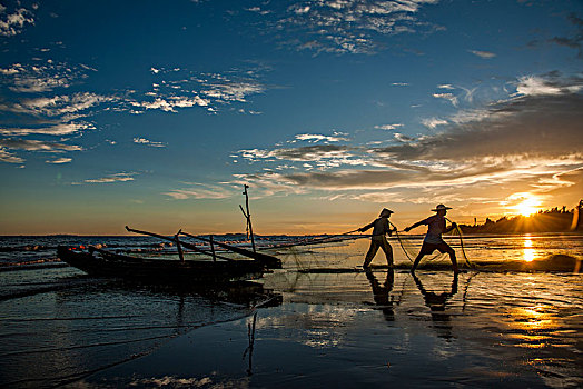 广西东兴京族万尾岛金滩渔民在晚霞中拖网捕鱼