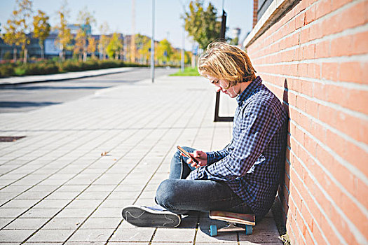 男青年,城市,玩滑板,坐,人行道,选择,智能手机,音乐