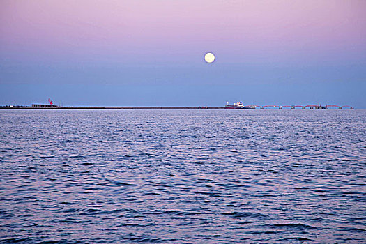 月亮下的蓝色大海和城市海岸线