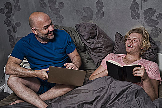 男性,坐,夫妇,向上,床上,笑,读,使用笔记本