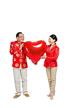 棚拍中国新年快乐的唐装老年夫妻捧红色心形气球