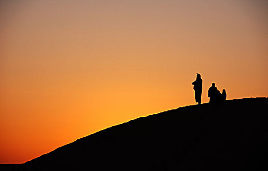 libya,grand,erg,oriental,ras,al-ghoul,silhouette,of,people,looking,at,the,colorful,sunset,on,sand,dunes