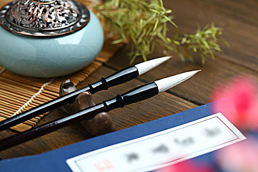 毛笔,线装书和香炉放在竹帘和木桌上
