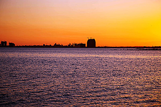 红色夕阳照映下的大海和城市的海岸线