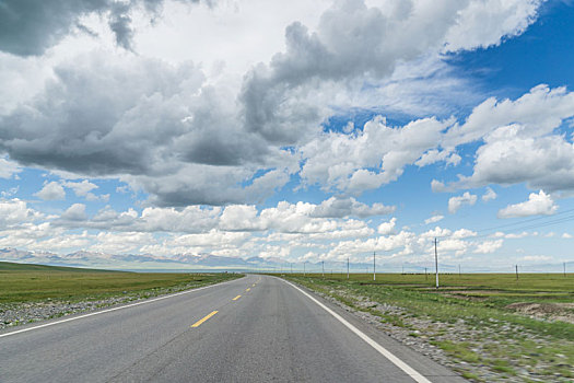 中国新疆夏季蓝天白云下高山草原g217独库公路直行道正面
