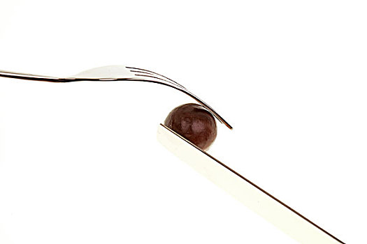 银色刀叉切开一个圆形棕色巧克力