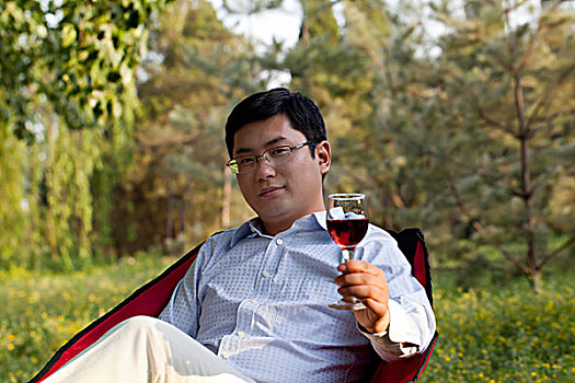 郊外坐在椅子上欣赏红酒的商务人士