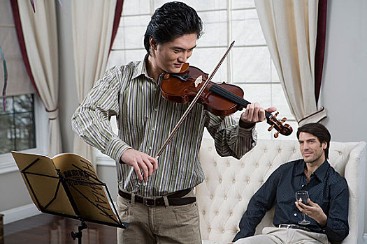 一位先生在拉小提琴另一位先生在倾听