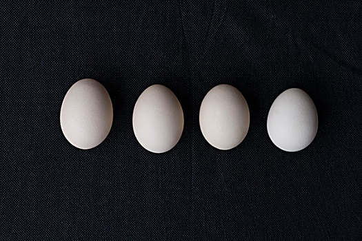 鸡蛋排列在黑色麻布背景上