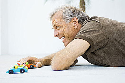 成熟,男人,躺着,地面,玩,玩具汽车,微笑,侧面视角