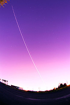 一架正在起飞中的飞机的灯光在夜空中形成了美丽的弧线