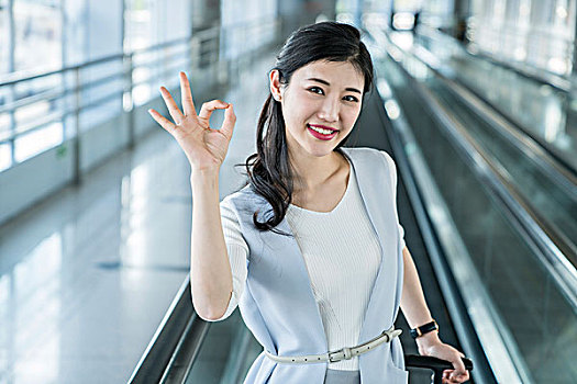 年輕商務女士在機場乘坐移動電梯