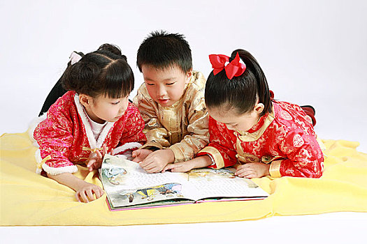 趴在毛毯上看书的三个小孩