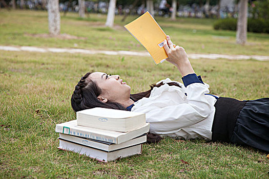 大学生躺在草地上看书