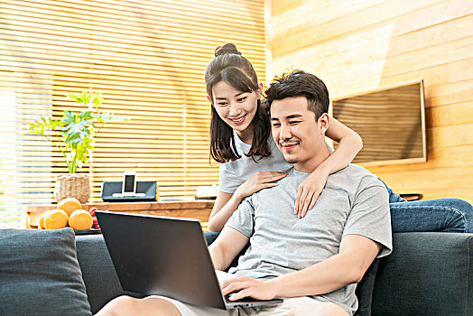 年轻情侣在沙发上使用电脑