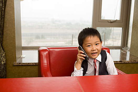 坐在书桌后面打电话的小男孩