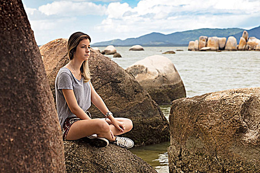 少女,坐,双腿交叉,岩石上,海洋,看别处