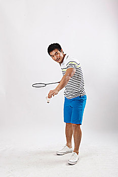 一个穿休闲装打羽毛球的青年男士