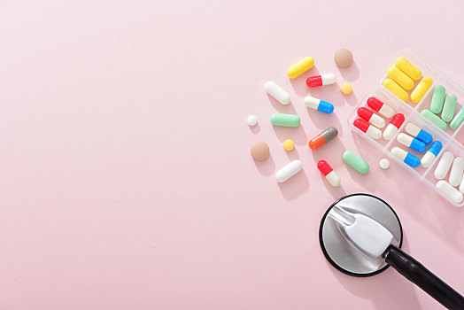 粉色背景上的药片和听诊器