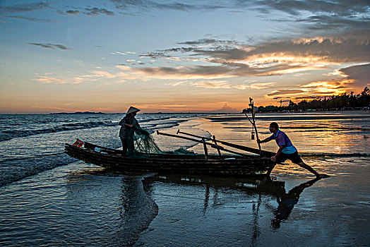 广西东兴京族万尾岛金滩渔民在晚霞中出海捕鱼
