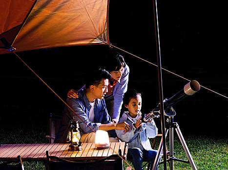 快乐的三口之家在户外使用天文望远镜