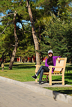 一名年轻女性在公园的椅子上休息