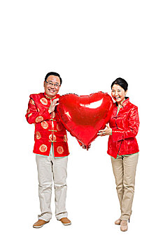 棚拍中国新年快乐的唐装老年夫妻捧红色心形气球
