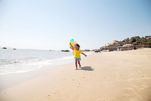 小女孩手拿气球在沙滩奔跑