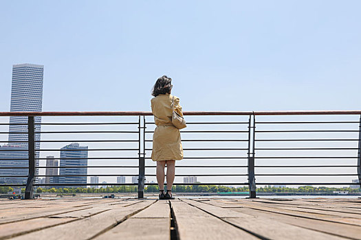 一个在江边观赏城市风景的女人站姿背影