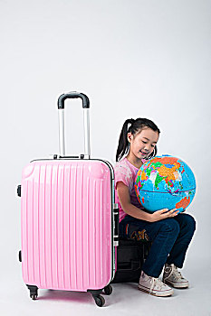坐在行李箱上抱着地球仪的小女孩