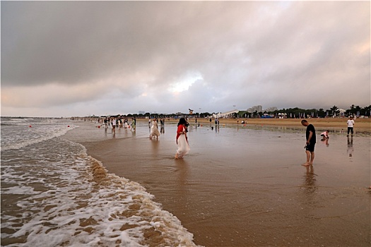 海边风起云涌变幻莫测,游客漫步沙滩赏景打卡