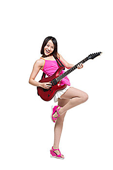棚拍时尚女青年边弹吉他边跳舞