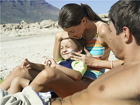 家庭,放松,海滩,男孩,4-6岁,坐,女人,施用,防晒霜,脸,侧面视角