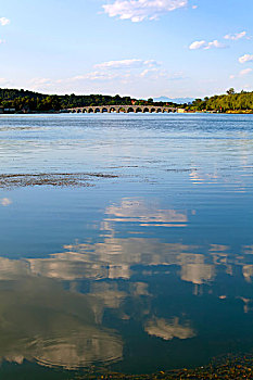 颐和园的昆明湖上倒映着白云和远处的十七孔桥