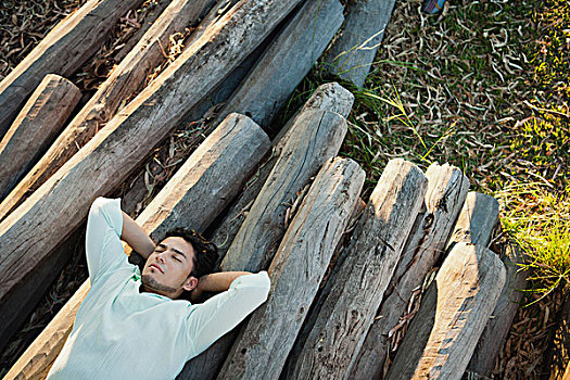 男青年,躺着,一堆木材,闭眼