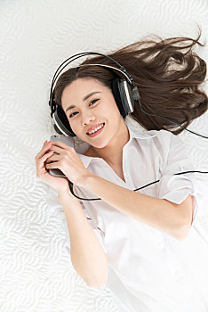 年轻女子躺在床上听音乐