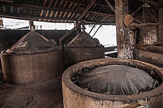 四川省乐山市犍为县罗城古镇酒厂工人正将发酵的酒糟放入发酵池子继续发酵