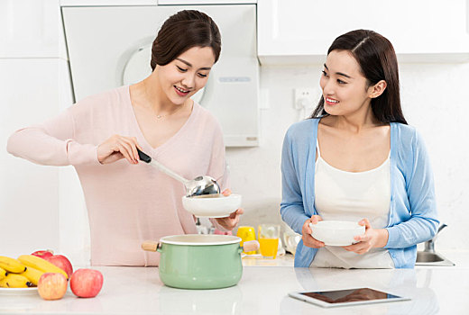 年轻女子在厨房边做饭边和朋友聊天