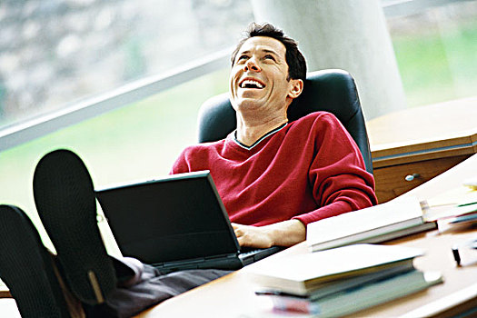 男人,坐,书桌,翘脚,拿着,笔记本电脑,笑