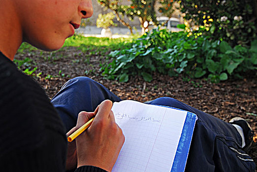 algeria,alger,midsection,of,a,schoolboy,writing,islamic,text,on,book