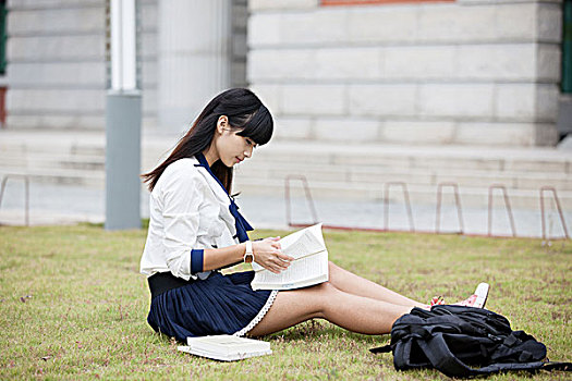 青年学生坐在草地上看书