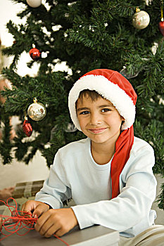 男孩,打开,礼物,正面,圣诞树,穿,圣诞帽,看镜头,微笑