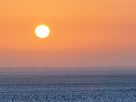 新疆哈密,雪后荒漠和落日余晖相映成景