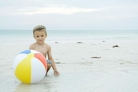 小男孩,蹲,后面,球,海滩,看镜头,微笑