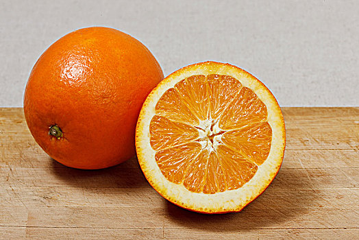 一个完整的橙子和一个对半切开的橙子
