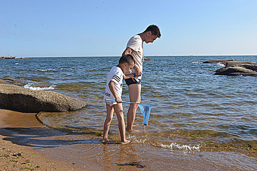 海边父子玩水捡贝壳玩水的快乐少年