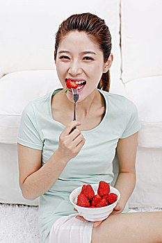 年轻女士坐在沙发旁吃草莓