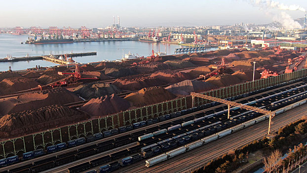 航拍港口生产作业现场,满载货物的火车从铁矿石堆场穿过